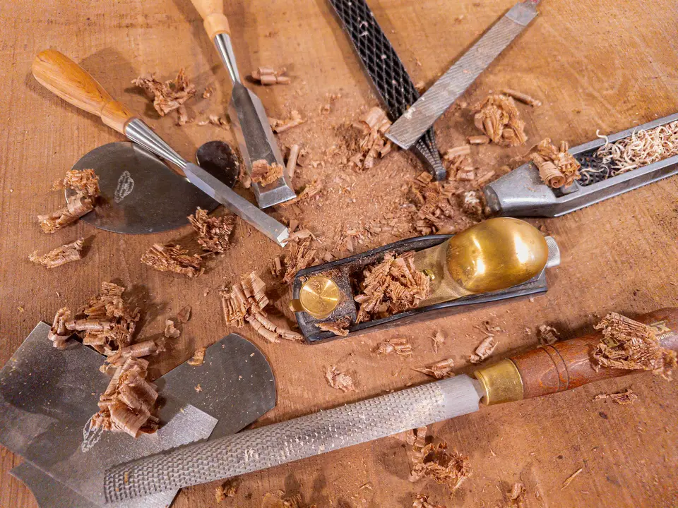 Chisels, rasps, a brass block plane and wood shavings on a workbench
